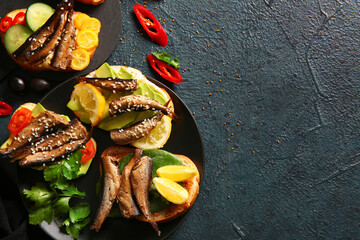 Plate of tasty sandwiches with canned smoked sprats on black background