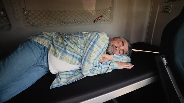 Senior truck driver sleeping in his cabin after working long routes overtime