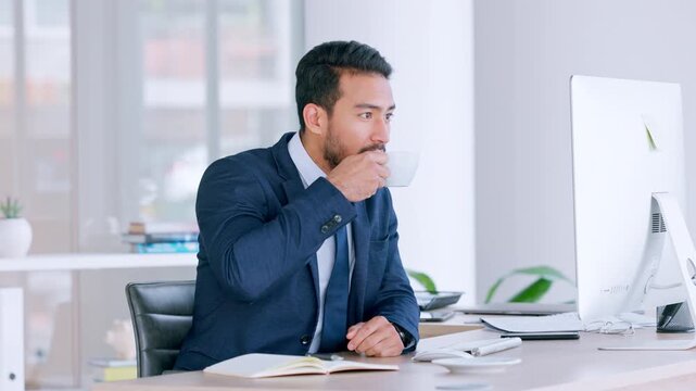 Investor happy with his progress. Confident business man drinking coffee while reading positive feedback on a desktop. Young professional worker sending emails while relaxing in a modern office