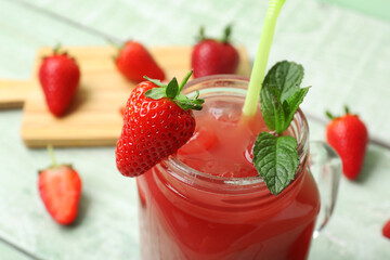 Mason jar of tasty strawberry juice green wooden table