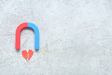 Magnet with paper broken heart on grunge grey background. Divorce concept