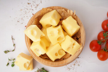 Bowl with pieces of Swiss cheese and tomatoes on white background