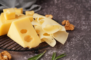 Stand with pieces of Swiss cheese and walnut on grey background