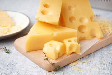 Board and plate with pieces of Swiss cheese on white table