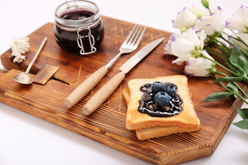 Board with jar of jam, toasts, blueberries and eustoma flowers isolated on white background