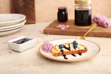 Plate with sweet blueberry jam toast and flowers on table