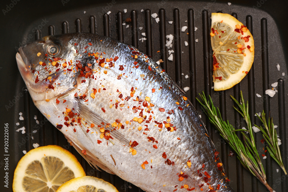 Poster raw dorado fish with lemon on grill pan