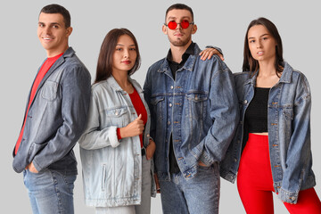 Group of young people in stylish denim jackets on light background
