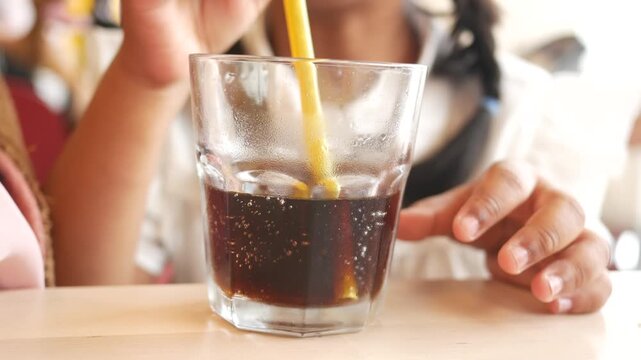 Little girl drinking soft drinks with a plastic straw 