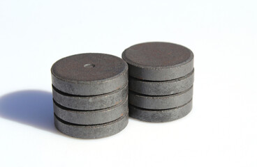 Two stacks of round, flat, dark-colored magnets against a white background