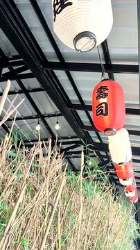 Vertical view of Japanese restaurant decoration with Japanese lanterns hanging and moving in the wind.