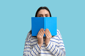 Young woman with book on blue background