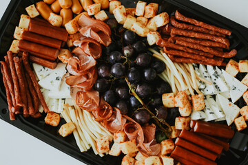 various snacks in the form of meats and cheeses with grape on a plate on a white background