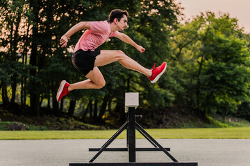 Obstacle course runner jumping a hurdle during outdoors training