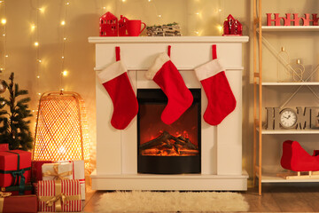 Stylish room with fireplace, festive socks and garlands decorated for Christmas celebration