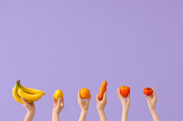 Hands with fresh vegetables and fruits on lilac background