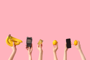 Hands with fresh fruits, payment terminal, credit card and smartphone on pink background