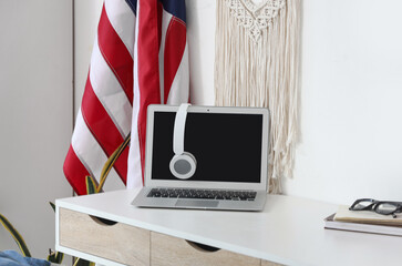 Comfortable workspace with laptop, USA flag and headphones in home office, closeup