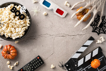 Top view of a Halloween-themed movie night setup with popcorn, 3D glasses, pumpkins, and spooky decorations