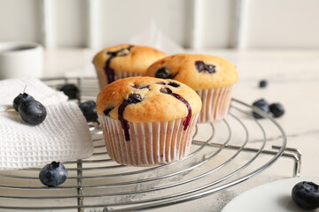 Cooling rack with tasty blueberry muffins on marble table, closeup