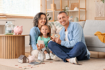 Happy family with calculator, piggy banks and money jars sitting on floor at home