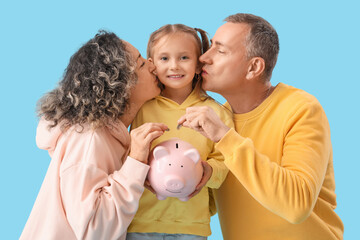 Happy family with piggy bank and coins on blue background