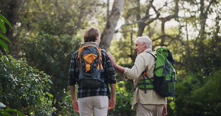 Father, son and hiking for fitness outdoor with backpacking support, trekking adventure and morning journey in forest. Senior man, family and comfort for travel exercise, bonding and explore nature