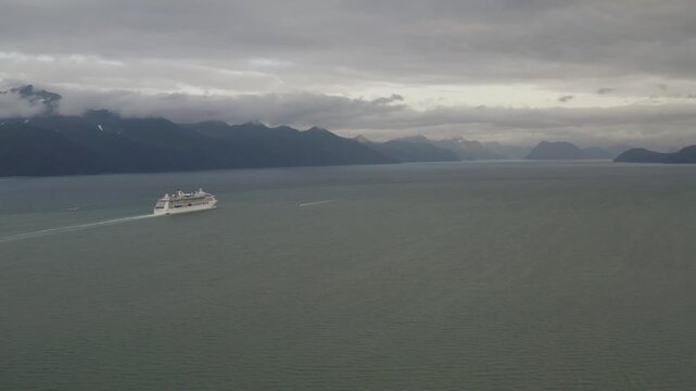 Panoramic view of cruiseliner ship leaving harbor port town of Seward, Alaska in Resurrection Bay headed towards Gulf of Alaska - 4K Drone
