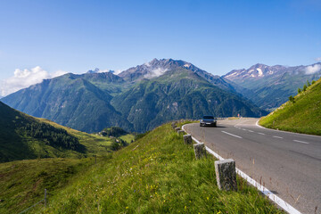 A lonely car rushes along a serpentine mountain road. Picturesque mountains are hidden in clouds....