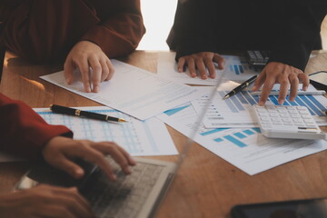 Group of confident business people point to graphs and charts to analyze market data, balance sheet, account, net profit to plan new sales strategies to increase production capacity.