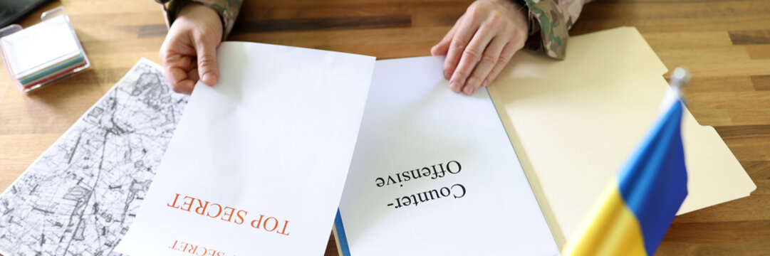 Military man holding in hands secret plans of Ukrainian counteroffensive operation - Powered by Adobe