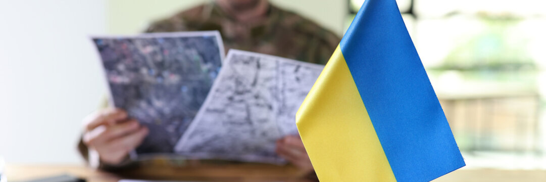 Military man holding in hands secret plans of Ukrainian counteroffensive operation closeup - Powered by Adobe
