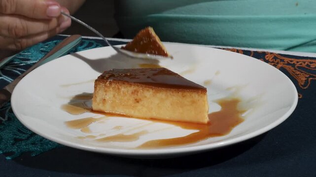 Woman hand cut venezuelan flan quesillo with spoon, typical latin american food