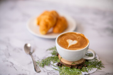 coffee cup with croissant with heart pattern