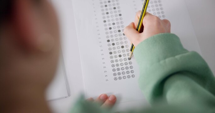 Above, exam and person at desk for education, paper and multiple choice assessment at school. Student, lesson or writing on document for answer, quiz or questionnaire in class for learning evaluation