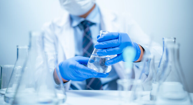 Researcher hand holds a beaker a test tube in a laboratory comparing samples for analysis in biology chemistry medicine, scientific experiment and technology