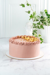 a whole cake decorated with nuts on white marble