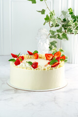 a whole cake decorated with fresh strawberries on white marble