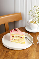 a piece of cake on a white plate, tea in a cup