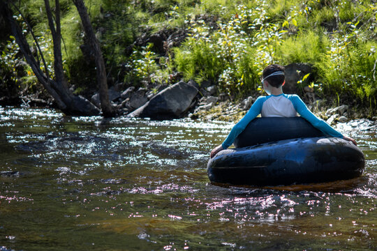 Boy floating down a creek on tubes, enjoying a peaceful outdoor moment
