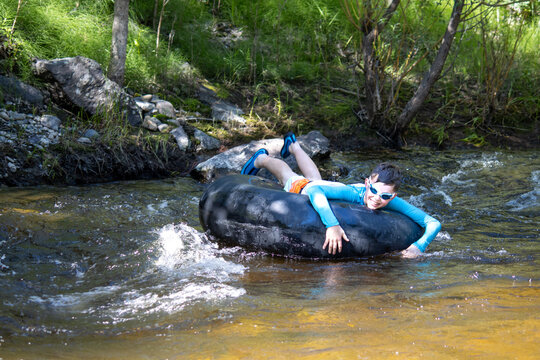 Boy enjoying tubing down a creek, wearing goggles and a rash guard