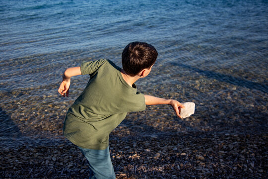 Boy skipping stones by the sea