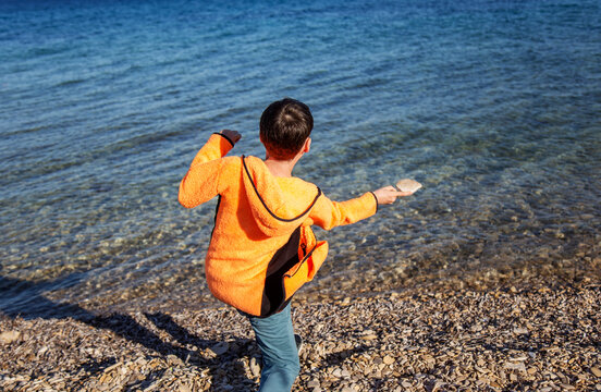 Boy skipping stones by the sea