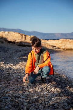 Cute boy stacked pebble stones tower on the beach