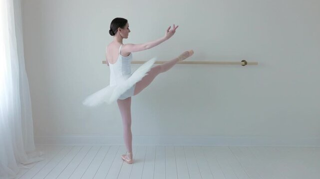 Ballerina stretching at Ballet Barre in white studio
