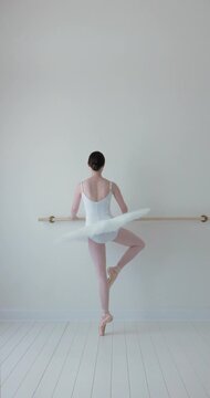ballerina en pointe facing the barre in white studio