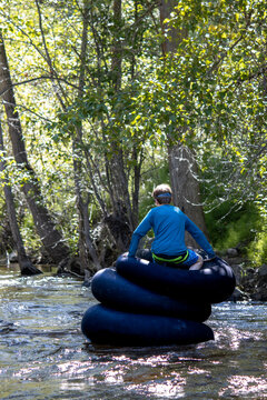 Boy floating on stacked inflatable tubes in a lush creek