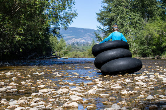 Boy standing in stacked inflatable tubes while in a shallow creek