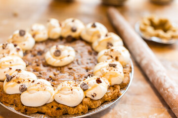 A freshly baked pie topped with whipped cream, chocolate chips,