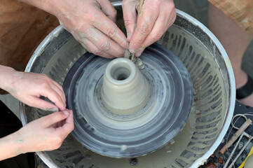 Potter helps to the child at a pottery master class.